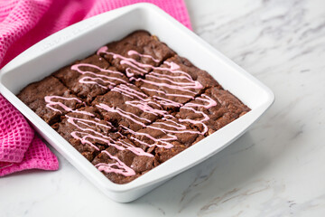 Pan of Homemade Brownies with Pink Frosting on a White Countertop