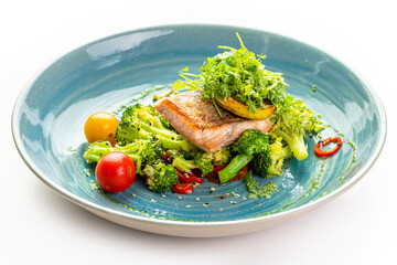 Grilled salmon fillet with lemon and fresh vegetables on a blue plate