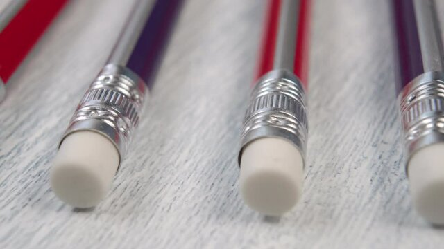 Row of multicolored pencils with white erasers with a metal aluminum attachment. On a wooden texture close-up. Macro shot. The concept of education and individuality