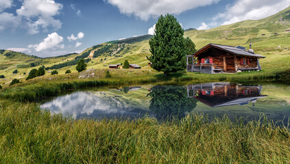 Fototapeta na wymiar Fabulous Mountain scenery in summer. Photo of wooden house on the shore of the lake, under sunlit on highland. Amazing nature landscape. Picture of wild area. concept of Travel and holiday on nature