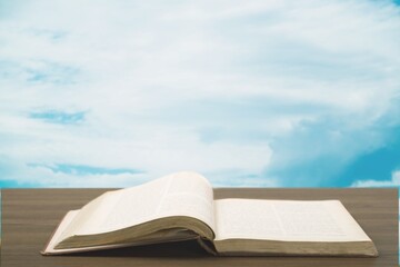 Holy Bible book on a wooden desk and sky background