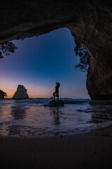 silhouette of a woman standing on a rock on the beach