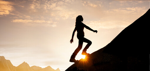Silhouette einer Frau beim Aufstieg  auf einen Berggipfel bei Sonnenaufgang
