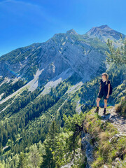 Fototapeta na wymiar Woman looking over valley in alps, mountain view with blue sky, Bavaria, Germany
