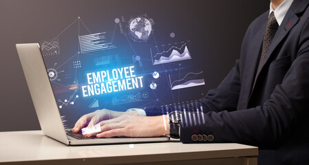 Businessman working on laptop with EMPLOYEE ENGAGEMENT inscription, new business concept