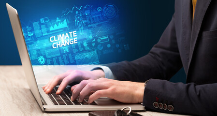 Businessman working on laptop with CLIMATE CHANGE inscription, cyber technology concept