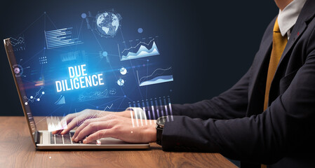 Businessman working on laptop with DUE DILIGENCE inscription, new business concept