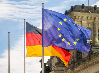 Flaggen von Deutschland und der Europäischen Union wehen im Wind vor dem Reichstag in Berlin. 
