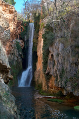 Fototapeta na wymiar Waterfall surrounded by vegetation and rocks