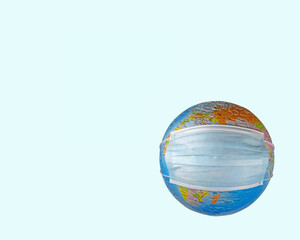 Face mask (N95) putting on a world globe protecting the world from pollution and infectious diseases (closeup, objects isolated on a blue background template, with copy space)