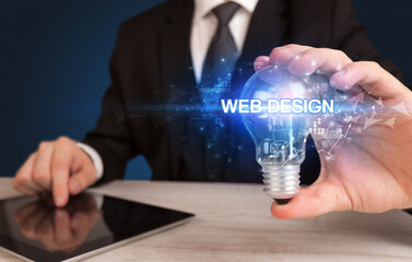 Businessman holding light bulb with WEB DESIGN inscription, innovative technology concept