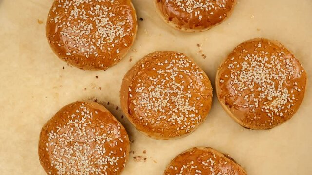 baked sesame buns on brown parchment paper, ingredient for a hamburger, top view