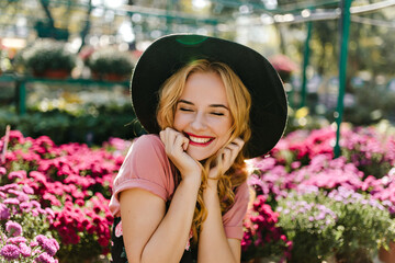 Fascinating female model with curly hairstyle laughing in garden. Lovable white girl expressing...