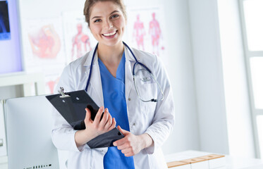 Woman doctor standing with folder at hospital