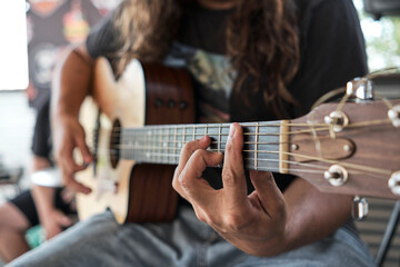 Fototapeta premium Man With Long Hair Playing Guitar. Selective focus on Hand Playing Chords.