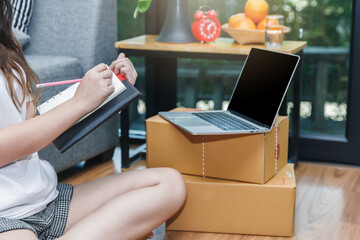 Successful entrepreneur business woman with online sales and Parcel shipping in her home office. Woman checking order on notebook.
