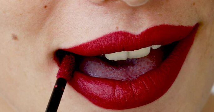 The close up shot of woman applying red lipstick