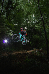 Professional mountain biker jump in forest