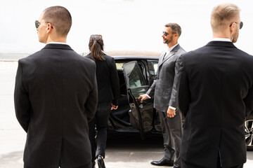 Bodyguards Protecting Businesswoman Opening Car Door