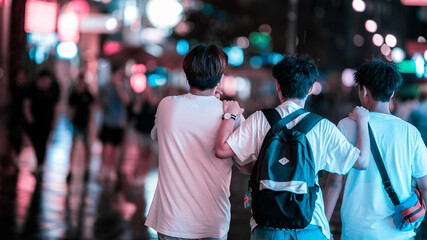 Group of friends having a good time at night. The lights of the streets give a nice bokeh and you can easily feel the fun they are about to have this night. 