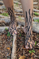 Feet with painted roots surrounded by roots in a park