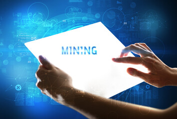 Hand holdig futuristic tablet with MINING inscription, new technology concept