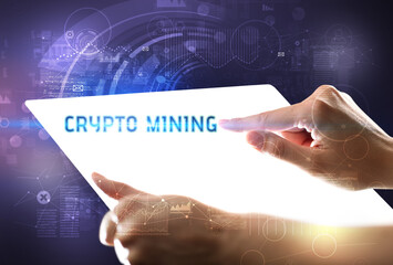 Hand holdig futuristic tablet with CRYPTO MINING inscription, new technology concept