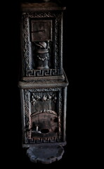 Vintage wood stove or fireplace from the late 1900s made in black cast iron with ornaments. Isolated on black.