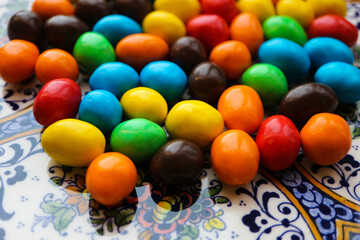 Fototapeta na wymiar colorful chocolate candies on the beautiful ornamental plate close up background