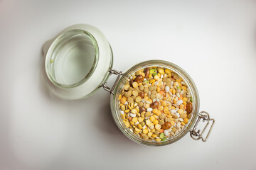 legumes in glass container, topdown view, bulk, white background