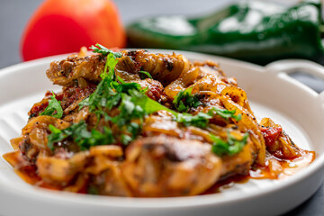 Spicy delicious chicken wings cooked with hot sauce and tomato with caramelized onions topped with chopped cilantro