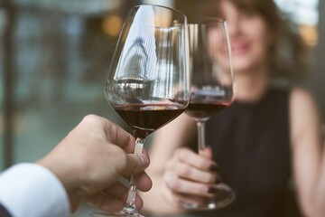 Happy couple drinking red wine. Selective focus on wine glass.