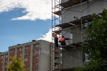 Scaffolding that provides sites for unfinished work on a new apartment building.Workers paint the walls