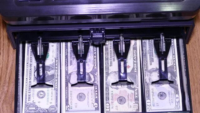 Cash register opening with us currency and coins.