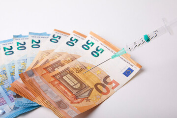 Seringue et billet de banque sur fond Blanc