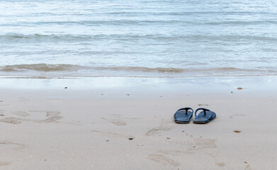 Fototapeta na wymiar A pair of black shoes on the beach.