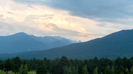 Evening mountain landscape at sunset. Silhouettes of the Pyrenees mountains and the cloudy sky are highlighted by the sun behind the mountains.