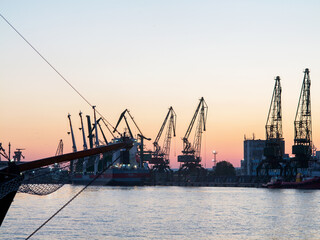 Fototapeta na wymiar Varna, Bulgaria - July 23, 2016: View on seaport with cranes, cargo and passenger ships at sunset, Varna.
