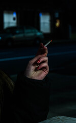 La mano de una mujer mientras sostiene un cigarro.