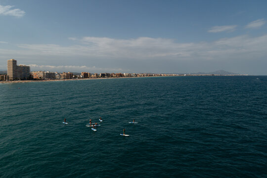 A group of people is practicing paddle surfing on the background of the sea city