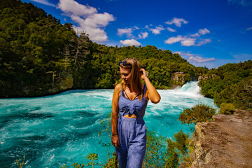young woman in sunglasses in front of a waterfallw