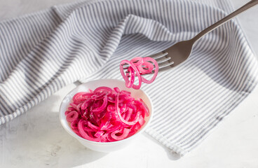 Juicy red onion marinated in lemon juice on a light background.