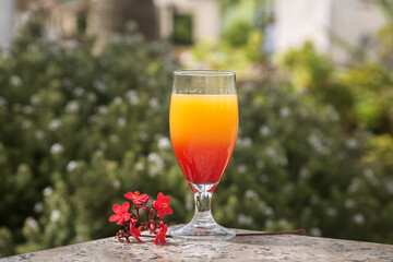 glass with a yellow-red two-layer cocktail on a green background