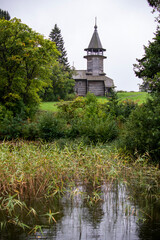 Obraz premium old wooden church on the island between trees in the rain