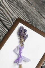 A bouquet of lavender in a photo frame. On brushed pine boards painted black and white.