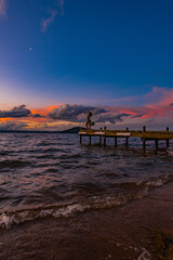 silhouette of a woman on a pier at the beach at sunset