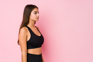 Young caucasian fitness woman doing sport isolated gazing left, sideways pose.