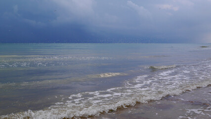 Rain Clouds Panorama at the Sea Horizon in the late afternoon. Blue waves, seagulls fly in the blue sky.