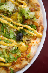 Indian style pizza with chicken and curry sauce and lettuce leaves