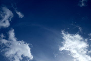 Obraz premium White clouds on intensive blue sky, high cirrus clouds in background, natural sun glare in bottom right corner, polarized light.